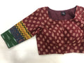 A women's maroon cotton blouse from VIKA Boutique, known as the 3/4 sleeve multicolour cotton blouse, showcases a vibrant floral pattern and a single long sleeve embellished with printed geometric and abstract designs in yellow, green, and blue.